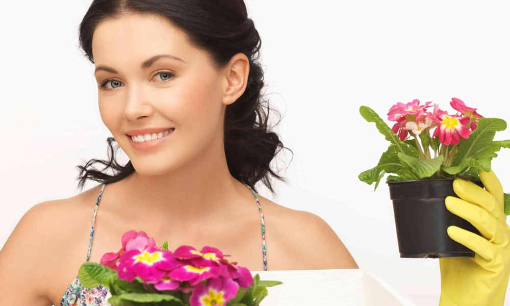 brunette woman with yellow glove holding a plant